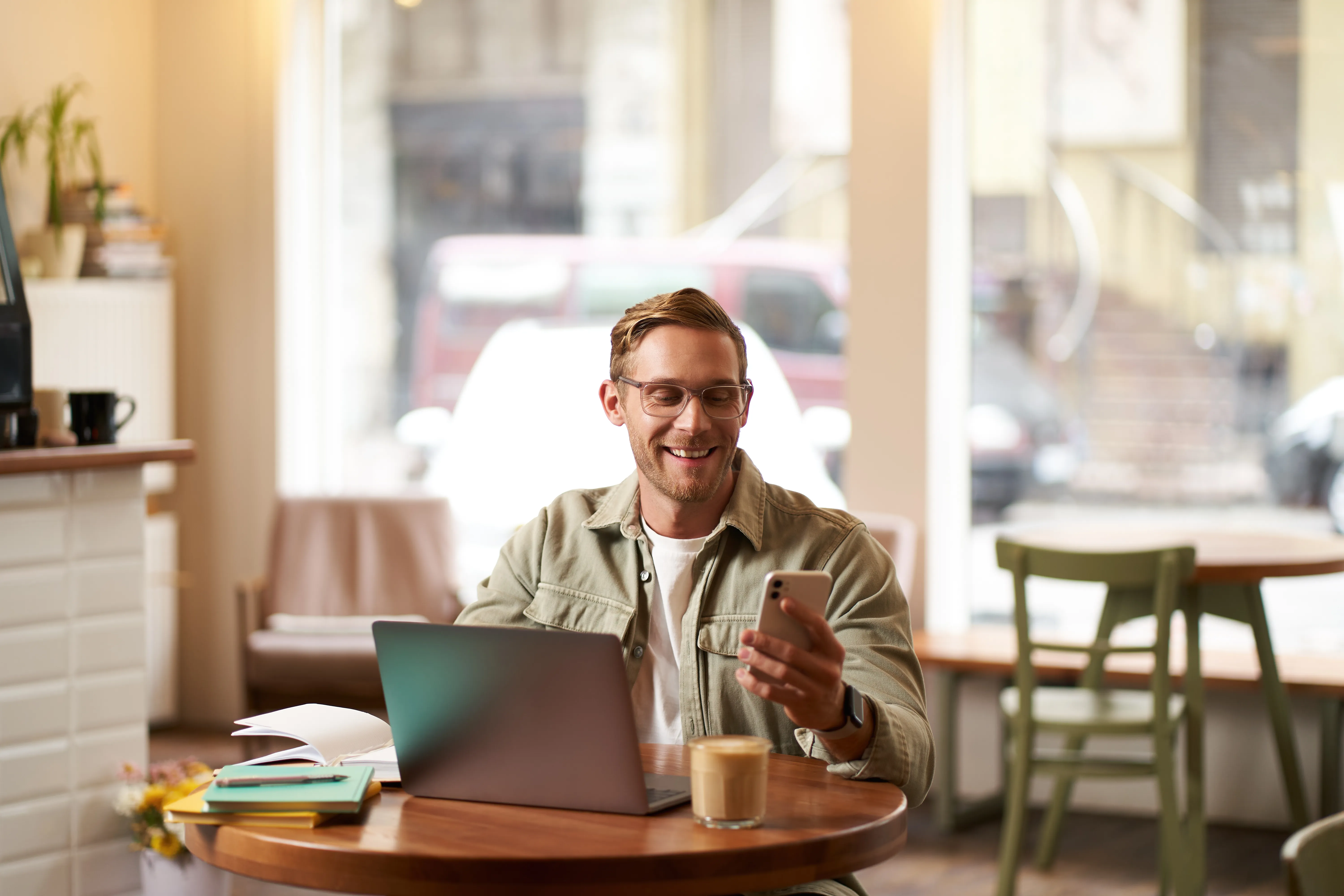 Portrait d'un homme consultant son téléphone au café avec son ordinateur portable
